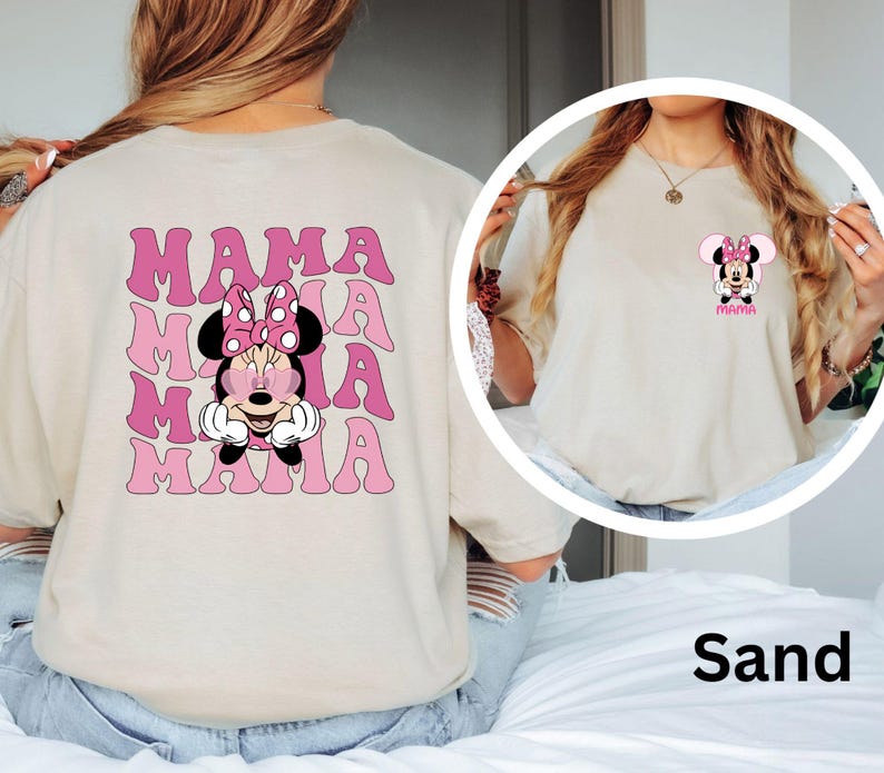 Puede incluir: Camiseta color arena con un dise&ntilde;o de Minnie Mouse y la palabra "MAMA" en rosa repetida varias veces. La parte delantera tiene un dise&ntilde;o m&aacute;s peque&ntilde;o de Minnie Mouse con la palabra "MAMA".