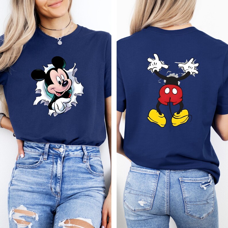 Puede incluir: Camiseta azul marino con un dise&ntilde;o de Mickey Mouse. La parte delantera muestra a Mickey Mouse saliendo de un efecto de papel rasgado. La parte trasera muestra los brazos, pantalones cortos y zapatos de Mickey. El gr&aacute;fico es en negro, rojo, amarillo y blanco.