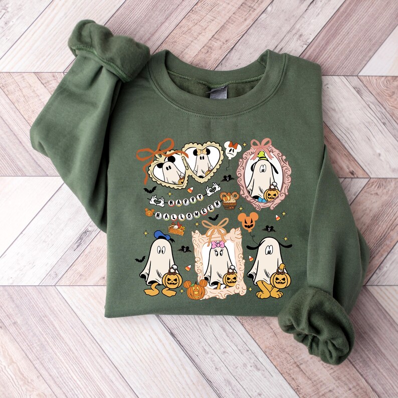 Puede incluir: Sudadera verde oliva con un dise&ntilde;o de Halloween. El gr&aacute;fico presenta fantasmas de dibujos animados, calabazas y murci&eacute;lagos, junto con el texto "Happy Halloween". El dise&ntilde;o incorpora elementos naranjas, negros y blancos.