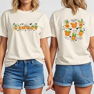 May include: Cream-colored t-shirt featuring Halloween-themed Mickey Mouse characters. The front displays a row of pumpkin-shaped characters with spiderwebs and bats. The back showcases more characters with the words "Mickey Mouse".
