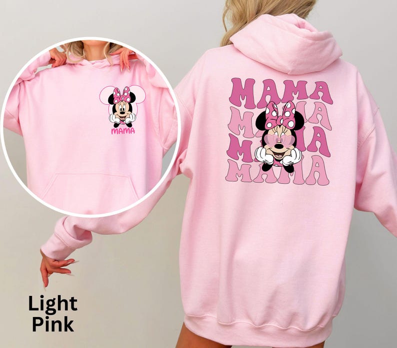 Puede incluir: Sudadera con capucha rosa claro con un dise&ntilde;o de Minnie Mouse en la parte delantera y trasera. La parte delantera muestra la cara de Minnie y la palabra "Mama". La parte trasera repite "Mama" con la cara de Minnie en el centro. La sudadera tiene un bolsillo delantero.