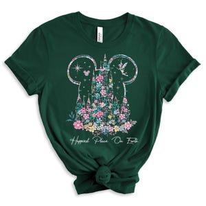 May include: A green t-shirt with a floral design of Cinderella's castle in the shape of Mickey Mouse ears. The text "Happiest Place On Earth" is printed below the design.