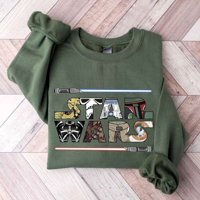 May include: A green sweatshirt with the word "STAR WARS" printed on the front. The letters are made up of images of characters from the Star Wars movies.