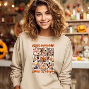 May include: A tan sweatshirt with a graphic print of Mickey Mouse and friends celebrating Halloween on the high seas. The text "Halloween High Seas" is printed on the sweatshirt.