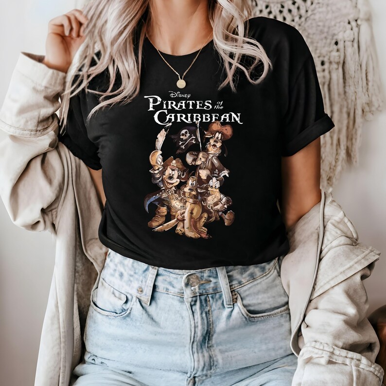 Pode incluir: Camiseta preta com um gr&aacute;fico de Mickey Mouse e seus amigos vestidos de piratas do filme da Disney Piratas do Caribe. O texto "Disney Pirates of the Caribbean" est&aacute; impresso na camiseta.