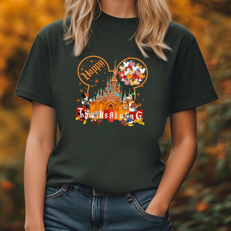 May include: Dark green t-shirt featuring a Thanksgiving design with the text "Happy Thanksgiving". The design includes a castle, Mickey Mouse, Minnie Mouse, Donald Duck, and Goofy. The design is in a cartoon style.