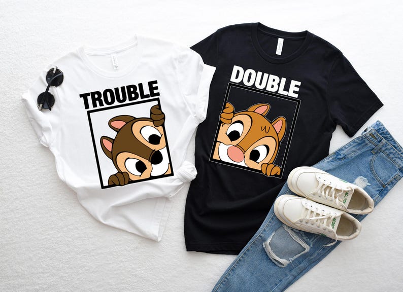 May include: Two t-shirts with a cartoon chipmunk peeking out of a frame. The white shirt says "Trouble" and the black shirt says "Double".