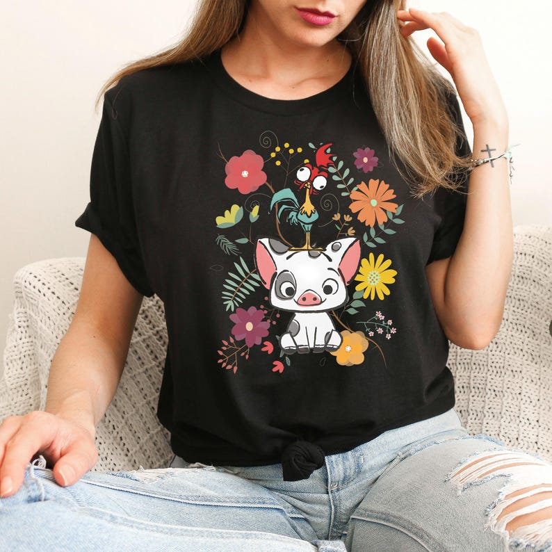 Puede incluir: Camiseta negra con una imagen de dibujos animados de un cerdo y un gallo rodeados de flores de colores.