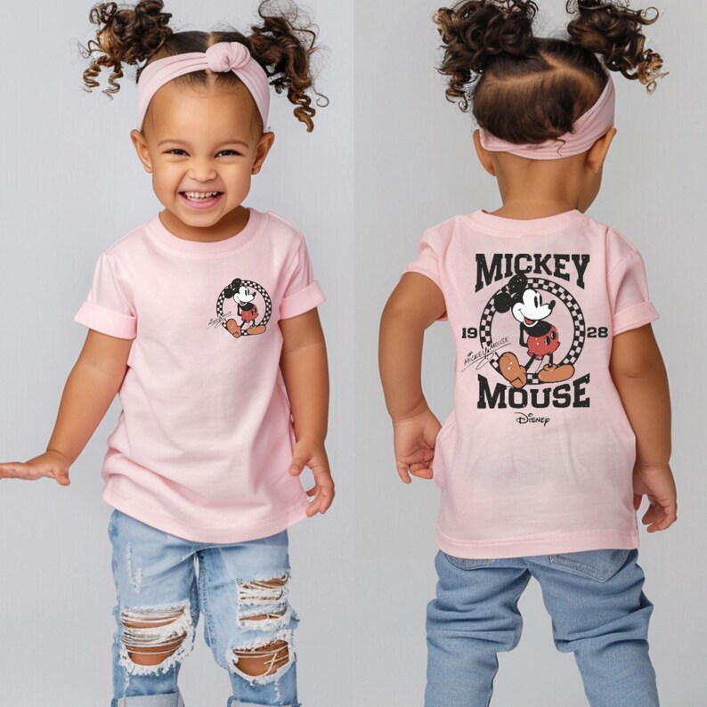 May include: Pink short-sleeved t-shirt with a black and white Mickey Mouse graphic on the front and a black and white Mickey Mouse graphic with the text "Mickey Mouse" on the back.