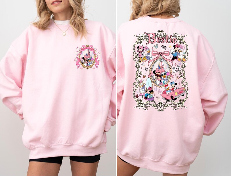 May include: Pink sweatshirt with a graphic of Mickey Mouse and friends in a vintage-inspired design. The text "Bestie" is printed on the back of the sweatshirt.