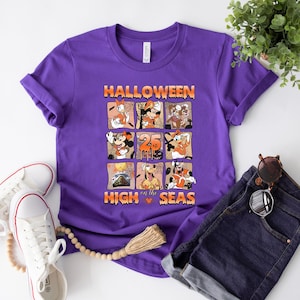 May include: Purple t-shirt with a graphic of Mickey Mouse and friends celebrating Halloween on a cruise ship. The text "Halloween on the High Seas" is printed on the shirt.