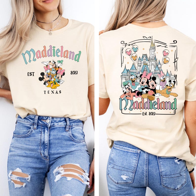 May include: A beige t-shirt with a graphic of Mickey Mouse and friends in front of Cinderella's Castle. The text "Maddieland Est. 2023" is printed on the shirt.