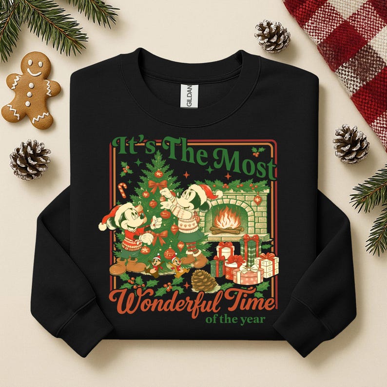 May include: Black sweatshirt with a Christmas design featuring Mickey and Minnie Mouse. The design includes a Christmas tree, fireplace, and the text "It's The Most Wonderful Time of the Year". Festive holiday apparel.