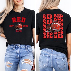 May include: Black t-shirt with a red graphic of a fire truck and the text "RED EST. 2006 CARS" on the front. The back of the shirt has the word "RED" repeated multiple times in a red, retro font.