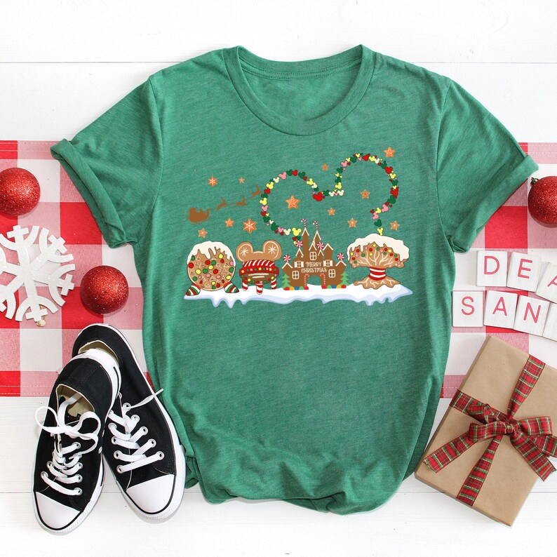 May include: Green t-shirt with a Christmas-themed design featuring gingerbread Mickey Mouse characters, a gingerbread castle, and a gingerbread tree. The design includes the text "Merry Christmas".