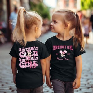 May include: Two children wearing black t-shirts with pink birthday girl designs featuring Minnie Mouse. One shirt says "Birthday Girl" with Minnie Mouse and "Est. 2012 Minnie Mouse". The other shirt says "Birthday Girl Birthday Girl 13" with Minnie Mouse.