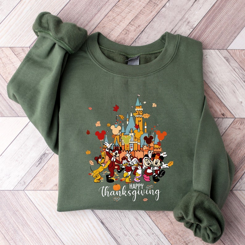 May include: Green sweatshirt with a graphic of Mickey Mouse and friends in front of the Disney castle. The text "Happy Thanksgiving" is printed below the image.