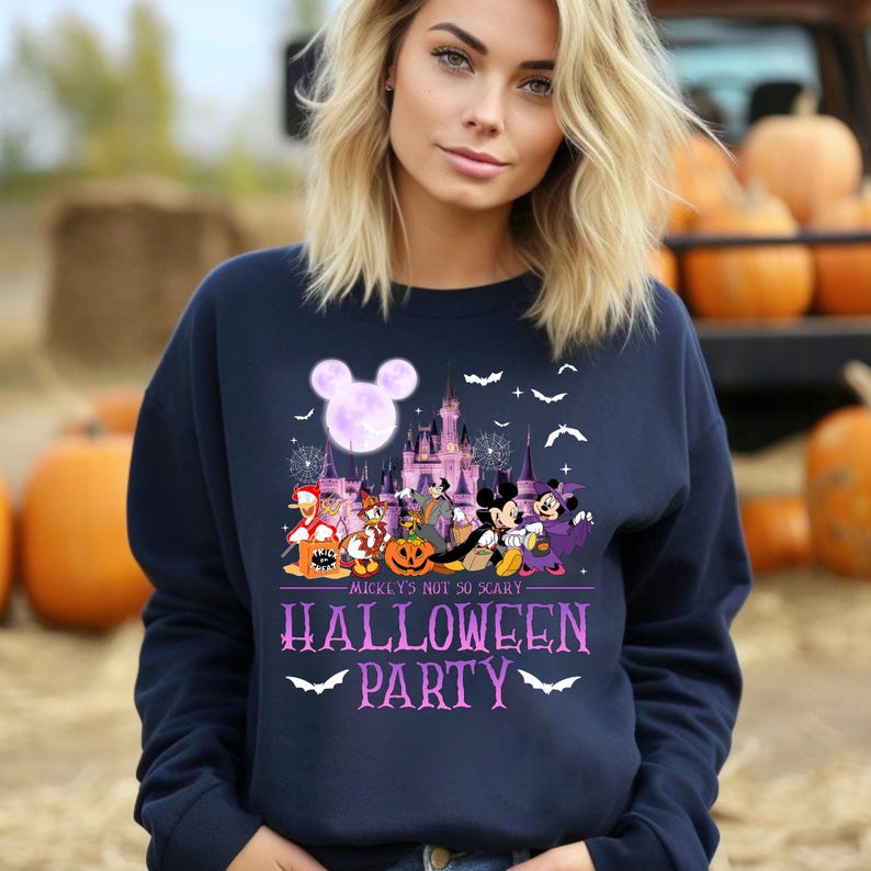 Puede incluir: Una sudadera azul marino con un gr&aacute;fico morado y blanco de Mickey Mouse y sus amigos frente al Castillo de Cenicienta. El texto "Mickey's Not So Scary Halloween Party" est&aacute; impreso debajo del gr&aacute;fico.