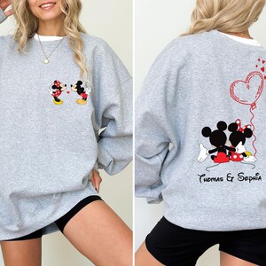 May include: Gray sweatshirt with a Mickey Mouse and Minnie Mouse graphic on the front and a heart with the text "Thomas & Sophia" on the back.