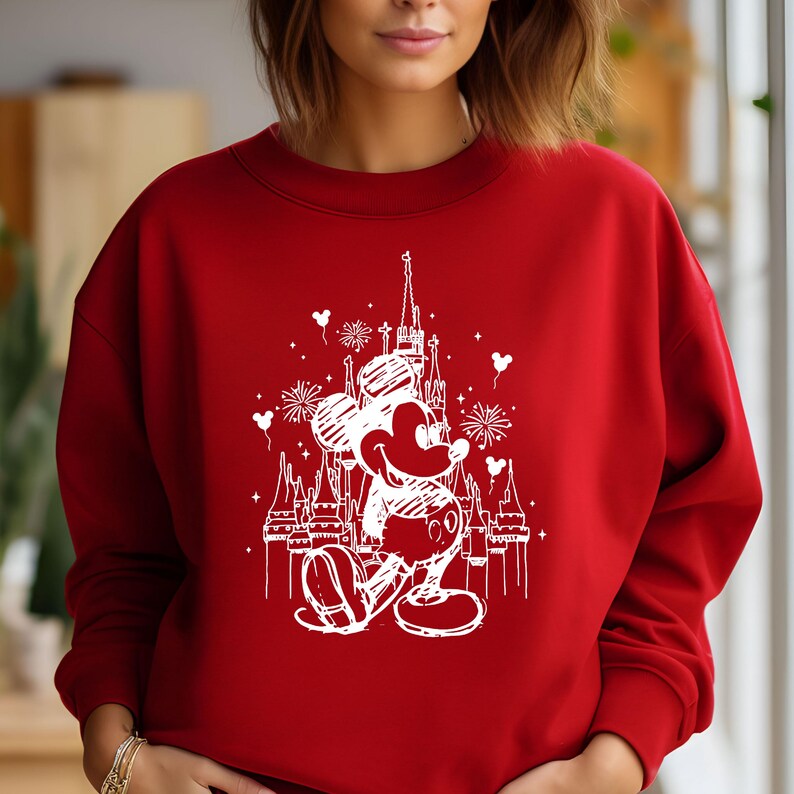 May include: Red sweatshirt with a white outline of Mickey Mouse in front of Cinderella's Castle. The design includes fireworks and balloons.