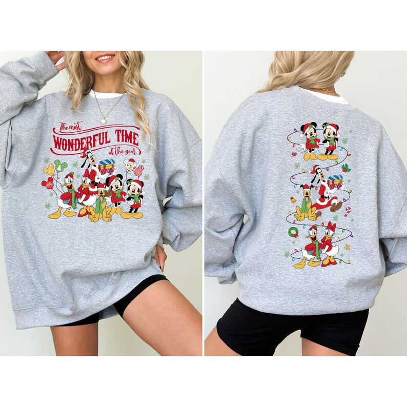 May include: A light gray sweatshirt featuring a festive Disney design. The front displays Mickey, Minnie, Donald, and Goofy in holiday attire with the text "The most WONDERFUL TIME of the year." The back has a vertical design of Disney characters.