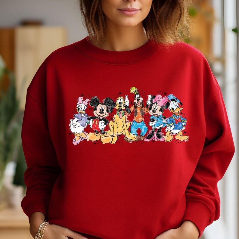 Puede incluir: Sudadera roja con un estampado gr&aacute;fico colorido de Mickey Mouse, Minnie Mouse, Donald Duck, Goofy y Pluto. Los personajes est&aacute;n dispuestos en l&iacute;nea y sonr&iacute;en.