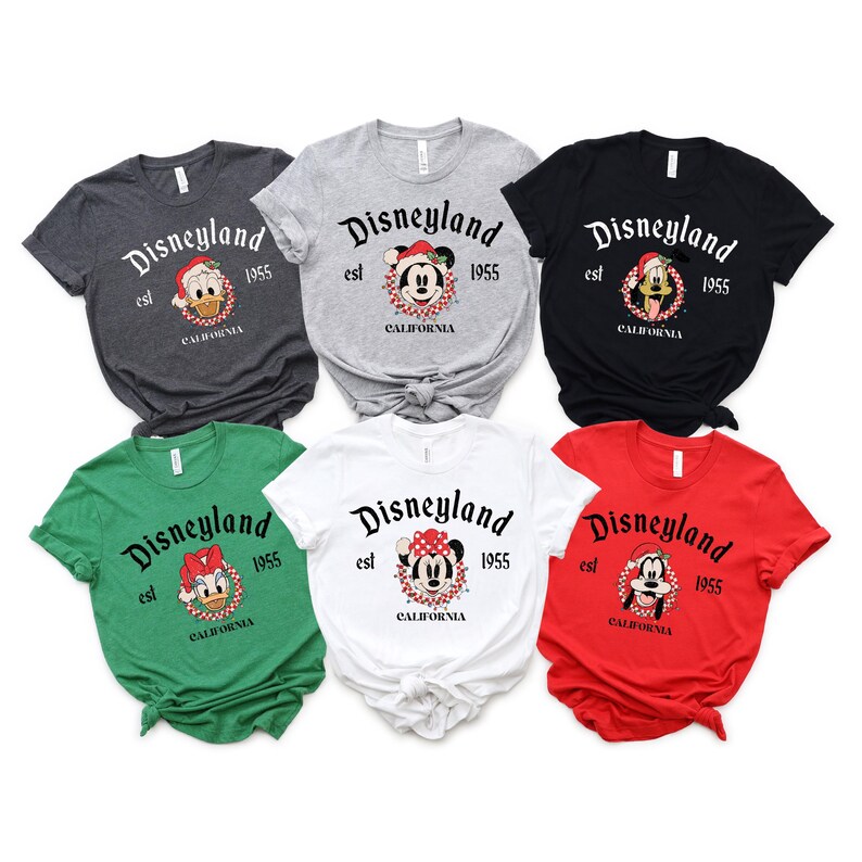 May include: Six different t-shirts with a Christmas theme featuring Mickey Mouse, Minnie Mouse, and Donald Duck. Each shirt has the text "Disneyland est 1955 California" printed on it.