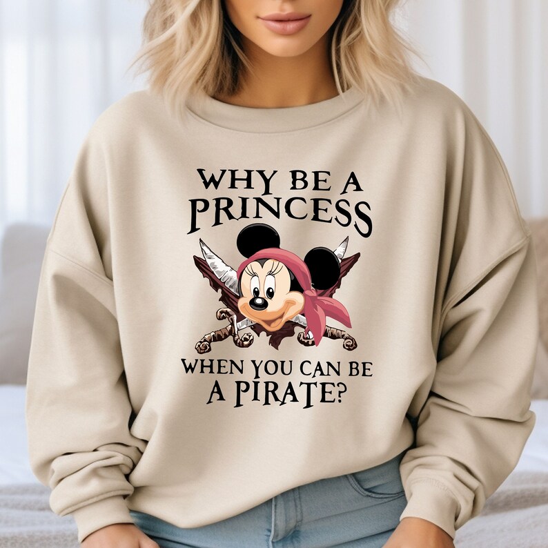 May include: A beige sweatshirt with a graphic of Mickey Mouse dressed as a pirate with the text "Why be a princess when you can be a pirate?"