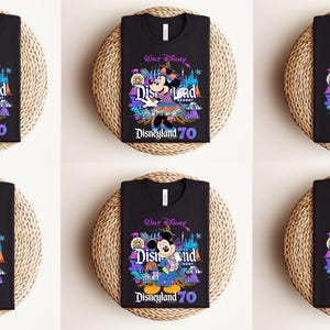 May include: Six black t-shirts with a colorful graphic design featuring various Disney characters. The shirts have the text "Walt Disney" and "Disneyland 70" printed on them.
