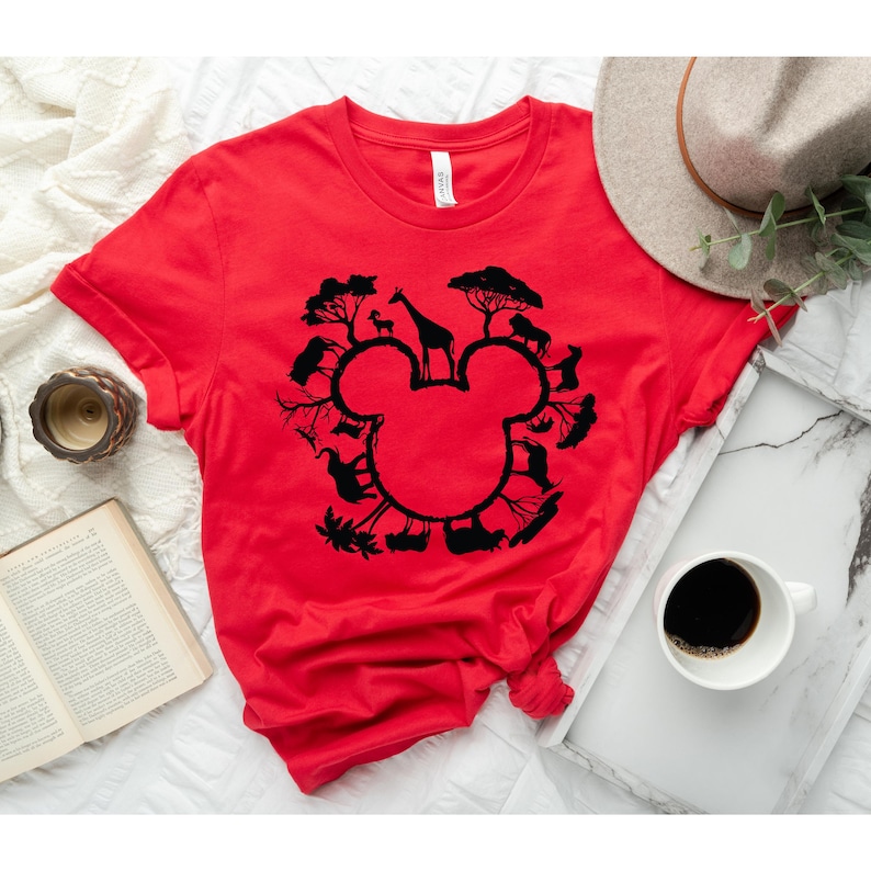 May include: Red t-shirt featuring a black silhouette of Mickey Mouse's head. The silhouette is formed by various animals and plants, creating a circle around the head.