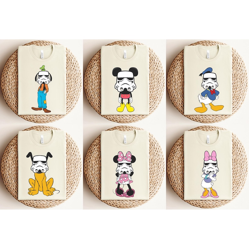 May include: Six beige t-shirts featuring cartoon characters with Stormtrooper helmets. Characters include Goofy, Mickey Mouse, Donald Duck, Pluto, Minnie Mouse, and Daisy Duck. Each shirt is displayed on a round, woven placemat.