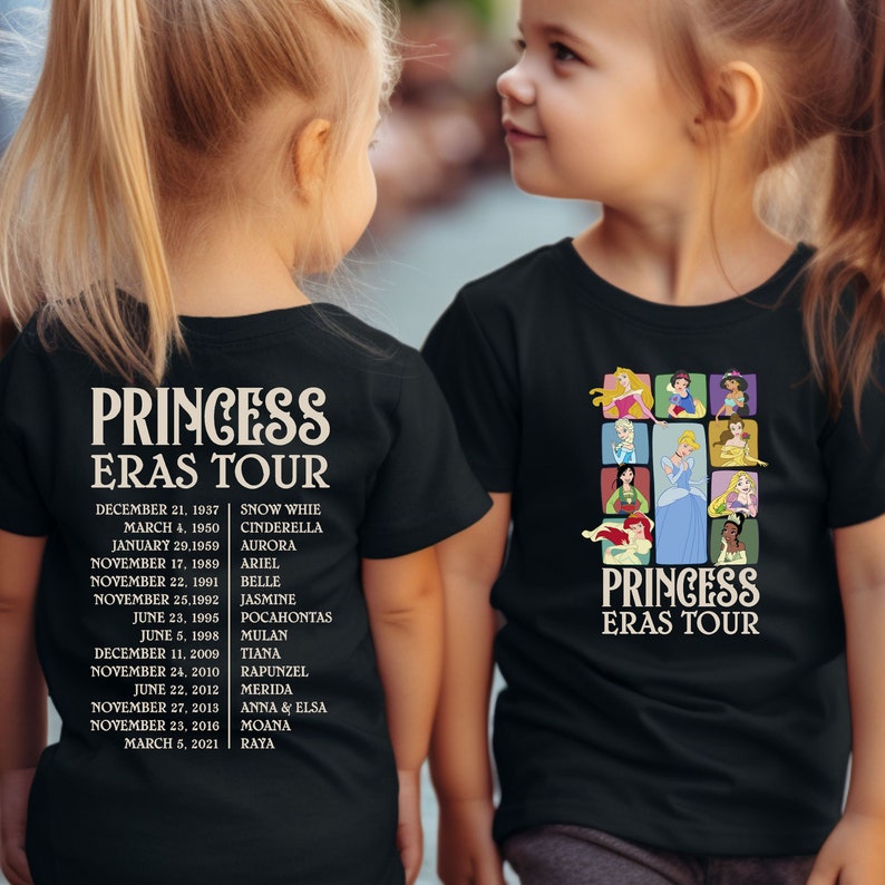 以下が含まれることがあります： プリンセスをテーマにした黒いTシャツを着た子供2人。Tシャツには、ディズニーのプリンセスのコラージュと「プリンセス・エラス・ツアー」の文字が書かれている。左側のTシャツの文字は、プリンセスの映画公開順に並んでいる。