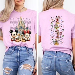 Puede incluir: Camiseta lila claro con Mickey Mouse, Minnie Mouse y Pluto con ropa festiva. La parte delantera tiene un castillo y texto. La parte trasera tiene un dise&ntilde;o de &aacute;rbol de Navidad con personajes de Disney.