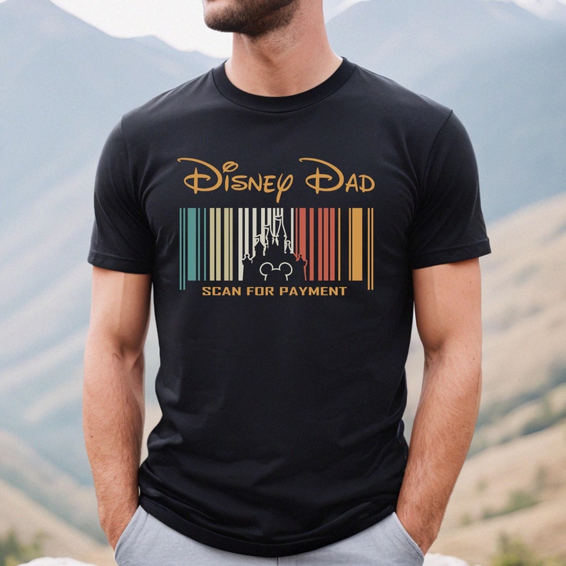 May include: Black t-shirt with a vintage-style graphic that says "Disney Dad" with a barcode and a silhouette of Cinderella's castle and Mickey Mouse. The text below the barcode says "Scan for Payment".