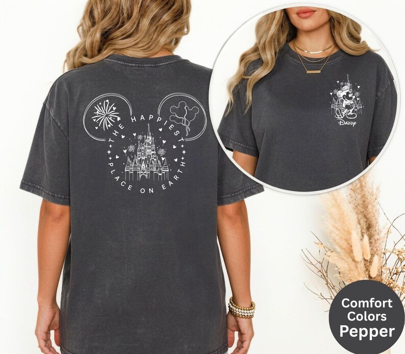 May include: Dark grey t-shirt with a white graphic on the back featuring a castle, fireworks, and the text "THE HAPPIEST PLACE ON EARTH". The front has a small graphic of Mickey Mouse and the word "Daddy".