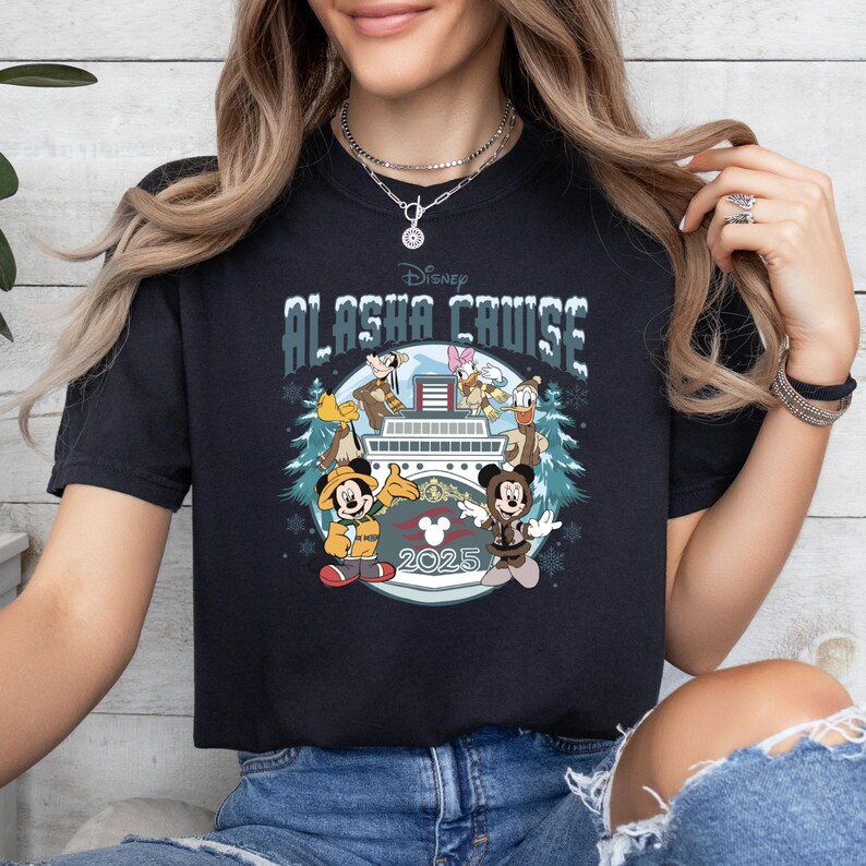 Pu&ograve; includere: T-shirt nero con la scritta "Disney Alaska Cruise" e illustrazioni di Topolino, Minnie, Paperino, Pippo e Paperina su una nave da crociera. &Egrave; presente anche l'anno "2025". La maglietta ha un girocollo.