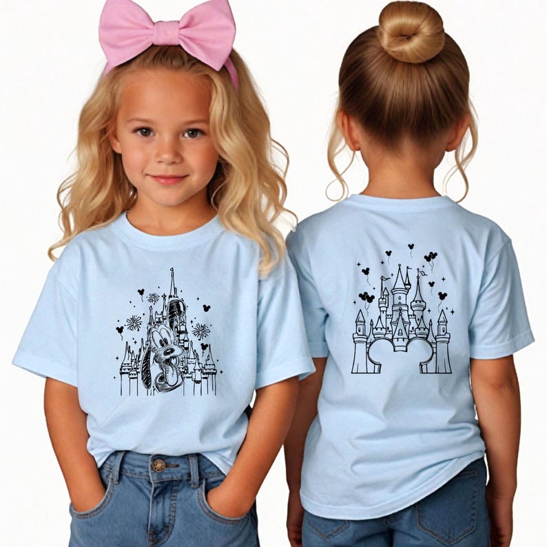 Puede incluir: Camisetas de color azul claro con dise&ntilde;os negros de castillos y personajes. Una camiseta presenta a Pluto y un castillo, la otra un dise&ntilde;o de castillo. Ambas camisetas son usadas por ni&ntilde;os. Las camisetas se combinan con vaqueros azules.