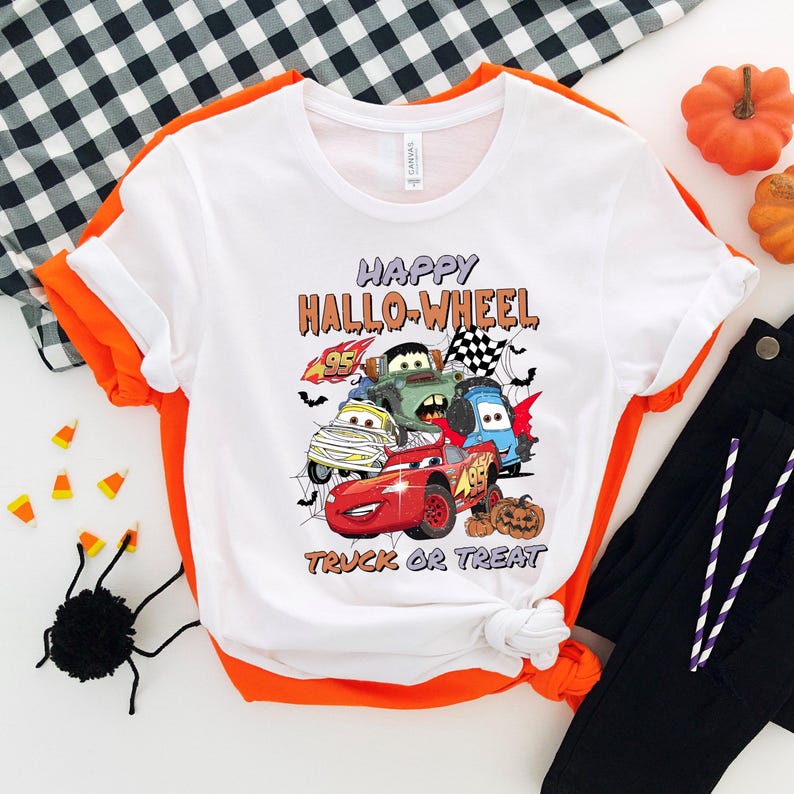 May include: White t-shirt with a graphic of cartoon cars from the movie Cars, with the text "Happy Hallo-Wheel Truck or Treat".