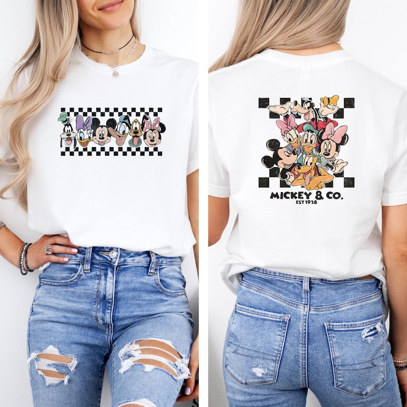 May include: White t-shirt featuring a group of cartoon characters on the front and back. The front design includes a checkerboard pattern with characters like Donald Duck and Mickey Mouse. The back design features Mickey & Co. EST 1928.