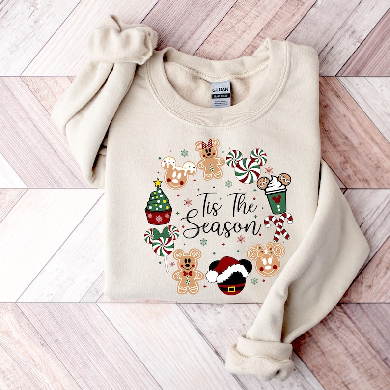 Peut inclure: Sweat-shirt cr&egrave;me avec un motif de No&euml;l festif. Le motif comprend des bonhommes en pain d'&eacute;pices, des cannes en sucre, un bonnet de P&egrave;re No&euml;l et le texte "Tis The Season" dispos&eacute; en cercle. Le sweat-shirt est en mati&egrave;re douce.