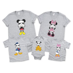 May include: A collection of gray t-shirts and a onesie featuring cartoon characters with Stormtrooper helmets. The characters include Mickey Mouse, Minnie Mouse, Donald Duck, a dog, and Daisy Duck. The shirts have short sleeves.