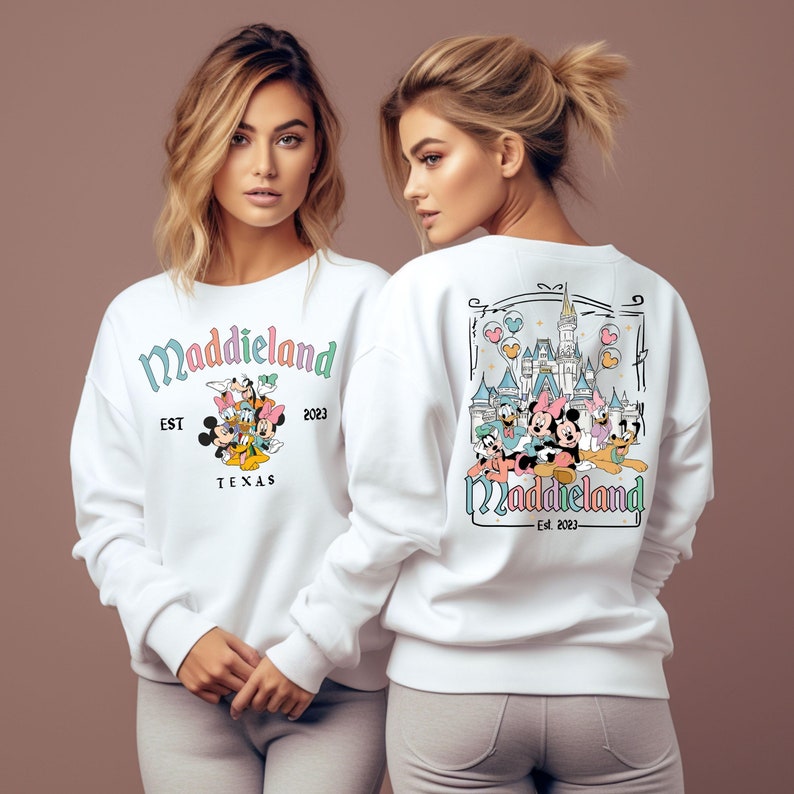 May include: White sweatshirt with a colorful graphic of Mickey Mouse and friends in front of Cinderella's Castle. The text "Maddieland Est. 2023 Texas" is printed on the front of the sweatshirt.