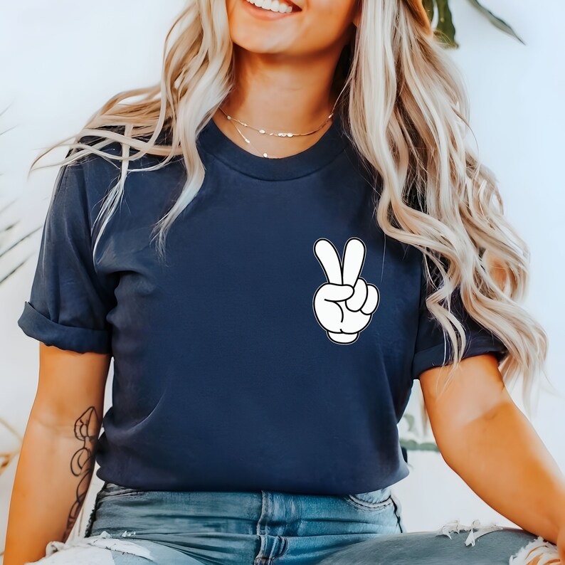 May include: A navy blue t-shirt with a white cartoon hand making a peace sign.