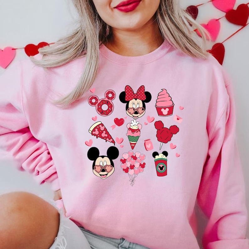 May include: Pink sweatshirt with a graphic print of Mickey Mouse and Minnie Mouse with hearts, donuts, pizza, ice cream, cotton candy, and a coffee cup.