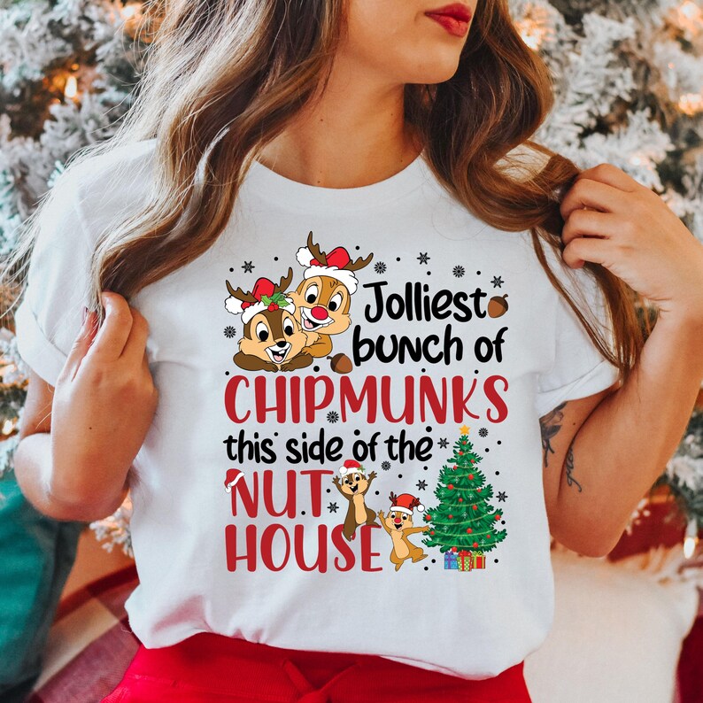 May include: White t-shirt with a Christmas-themed design featuring three cartoon chipmunks, a Christmas tree, and the text "Jolliest bunch of Chipmunks this side of the Nut House".