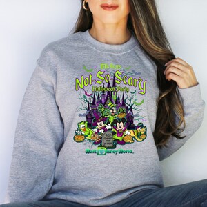 May include: Gray sweatshirt with a green, purple, and black graphic of Mickey Mouse and friends in front of a castle. The text "Mickey's Not-So-Scary Halloween Party" is above the graphic and "Walt Disney World" is below the graphic.
