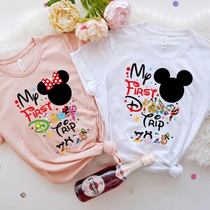 Peut inclure: Deux t-shirts &agrave; manches courtes, un rose blush et un blanc, sur le th&egrave;me de Disney. Le t-shirt rose pr&eacute;sente un design Minnie Mouse avec un n&oelig;ud rouge. Les deux chemises portent l'inscription "My First Disney Trip 2025".