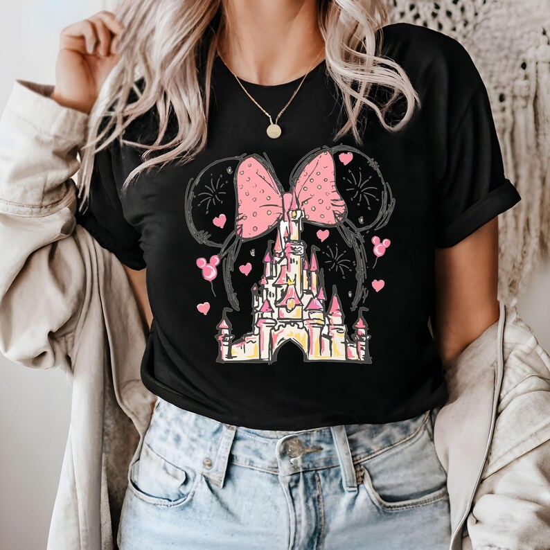 May include: Black t-shirt with a pink bow and a cartoon drawing of a castle with fireworks. The castle is pink and yellow.