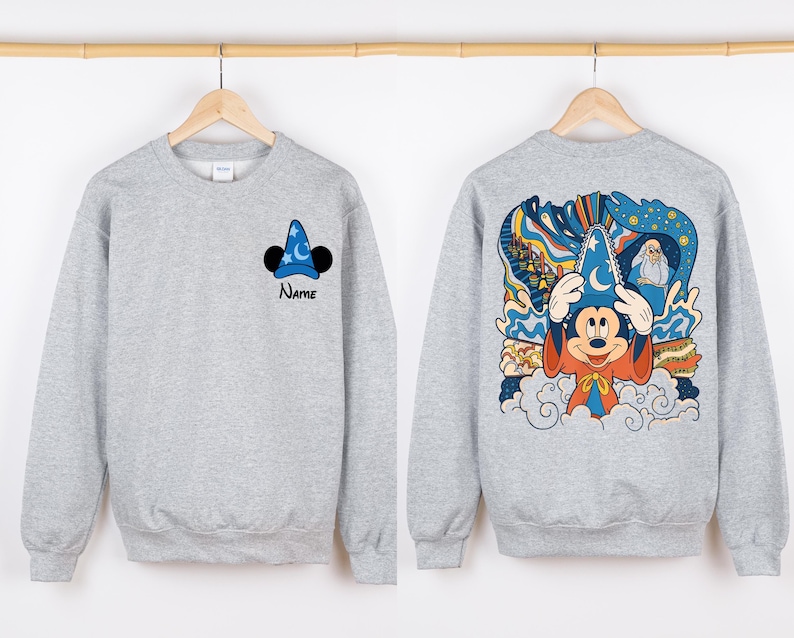 May include: Gray sweatshirt with a Mickey Mouse illustration wearing a sorcerer hat on the back. The front of the sweatshirt has a smaller Mickey Mouse sorcerer hat illustration and the word "Name" underneath.