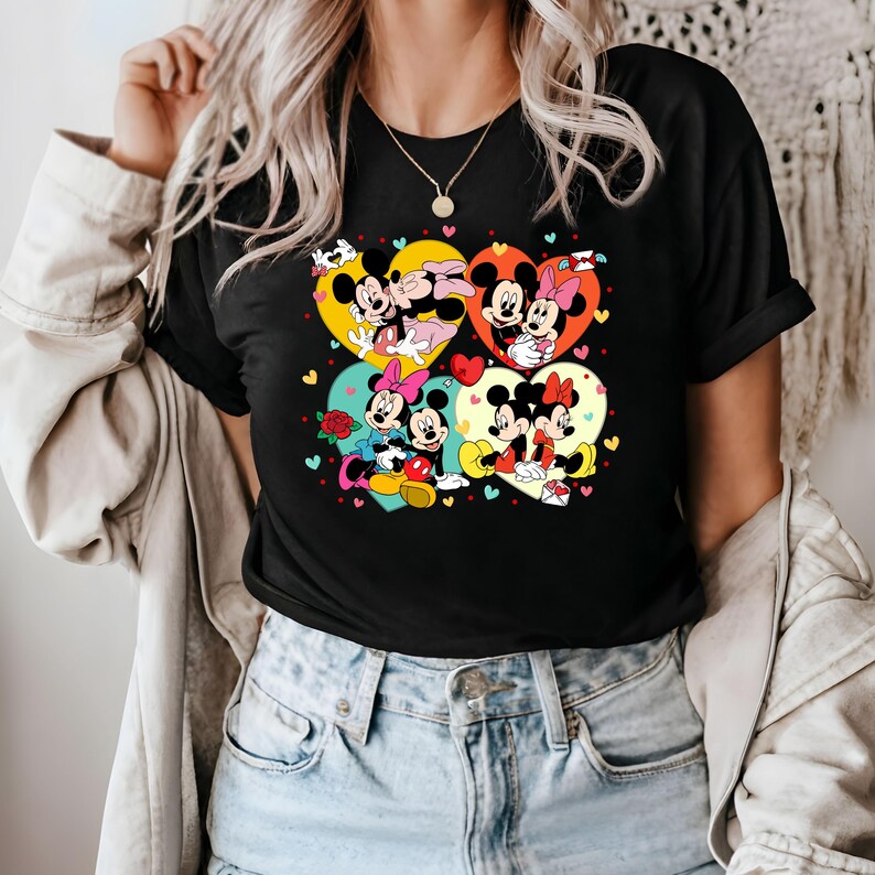 May include: Black t-shirt with a graphic print of Mickey Mouse and Minnie Mouse in various poses within hearts. The hearts are surrounded by small hearts in various colors.
